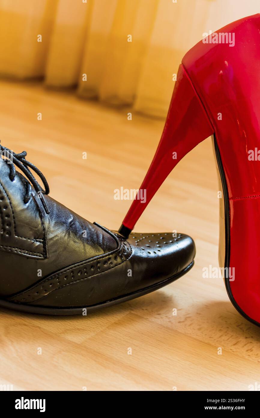 Una donna calpesta un uomo con i tacchi alti. Foto simbolica per eguaglianza e bullismo. Austria Foto Stock