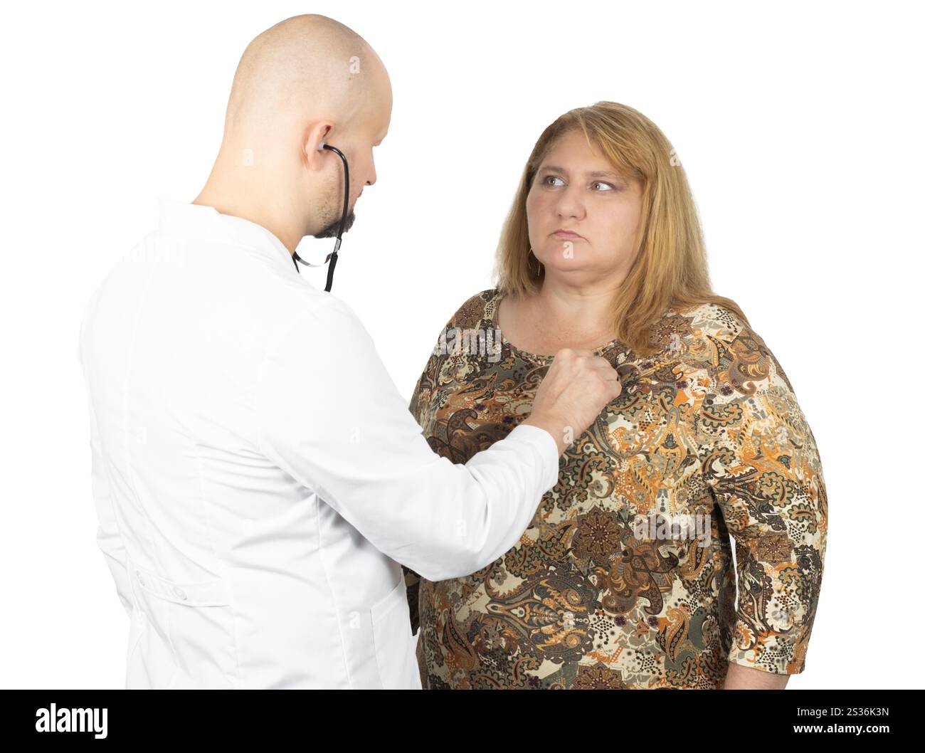 Un medico di sesso maschile con un camice bianco sta usando uno stetoscopio per esaminare il torace di una paziente. Foto Stock