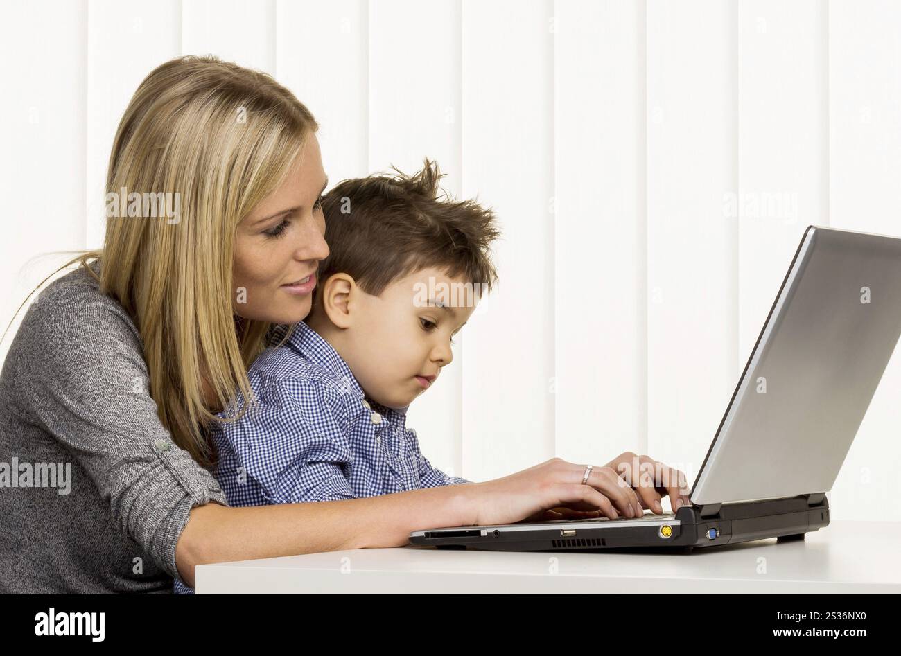 Madre e figlio al computer, simbolo di lavorare da casa, famiglia e carriera, doppio fardello Foto Stock