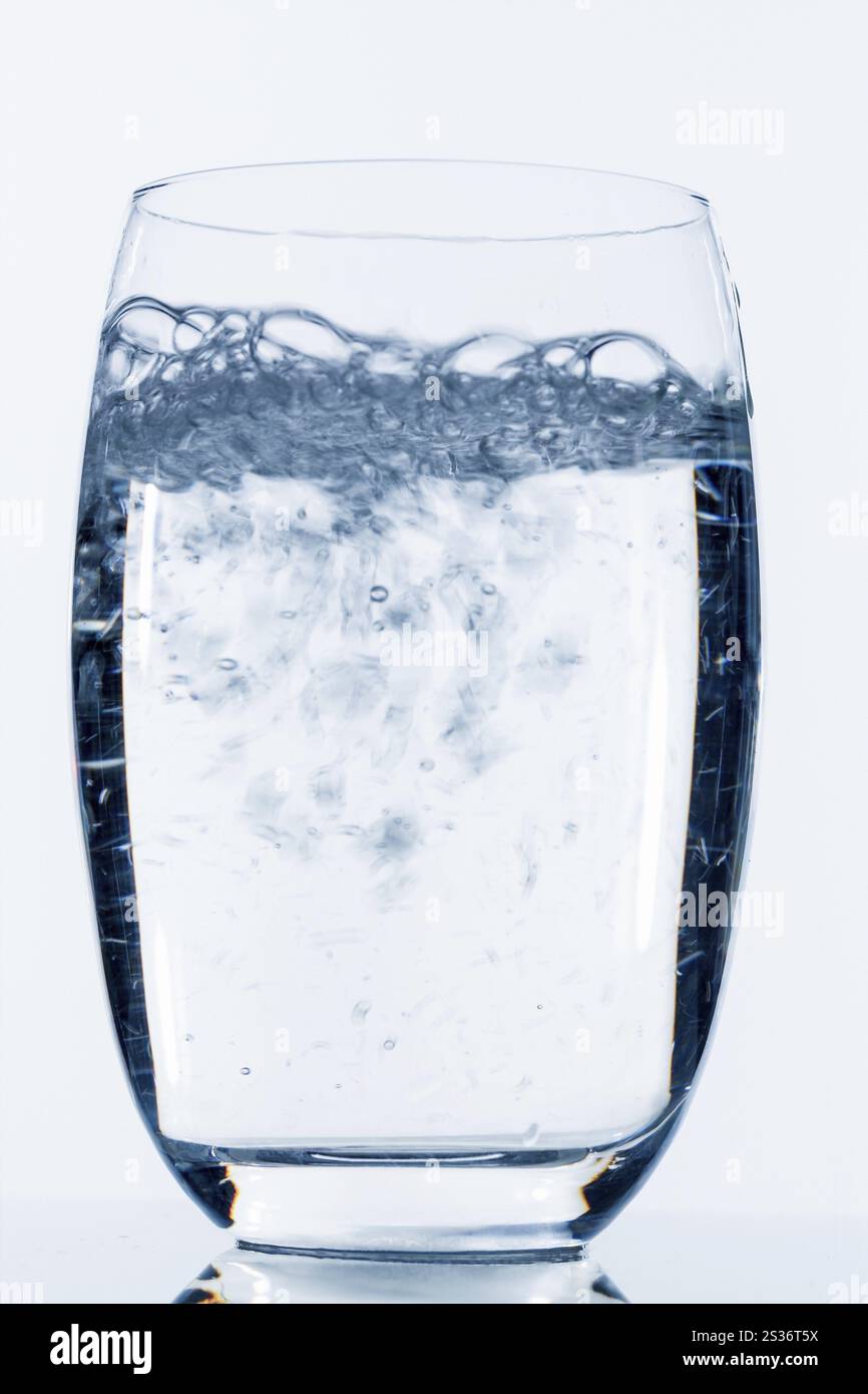 L'acqua viene versata in un bicchiere, simboleggiando l'acqua potabile, la freschezza, la domanda e il consumo Foto Stock