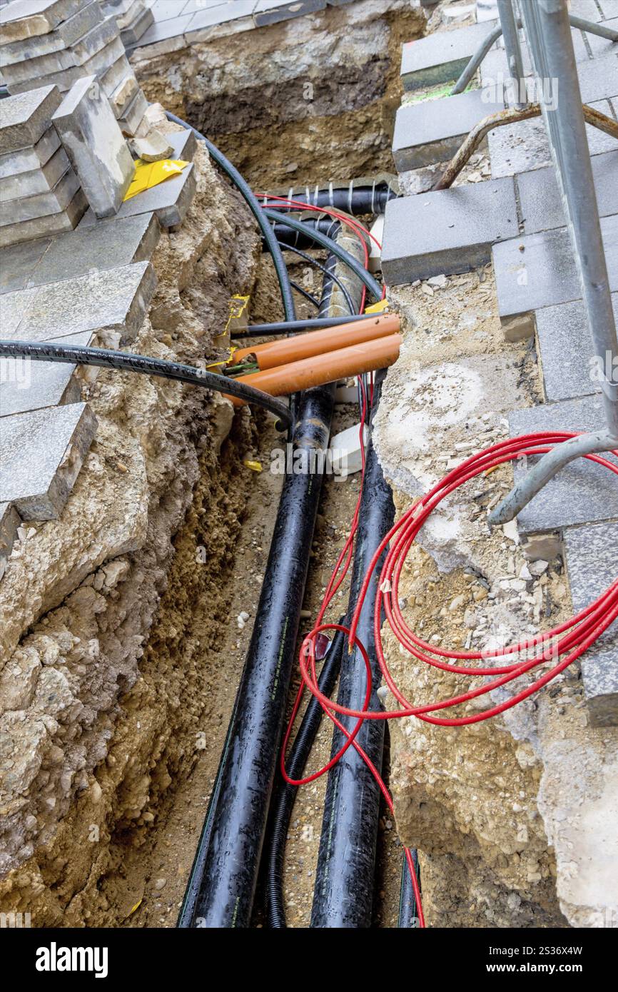 Nuovi tubi per l'acqua, il riscaldamento, il teleriscaldamento e l'elettricità sono in fase di posa in cantiere. Pozzo di scavo con linee di rifornimento Austria Foto Stock