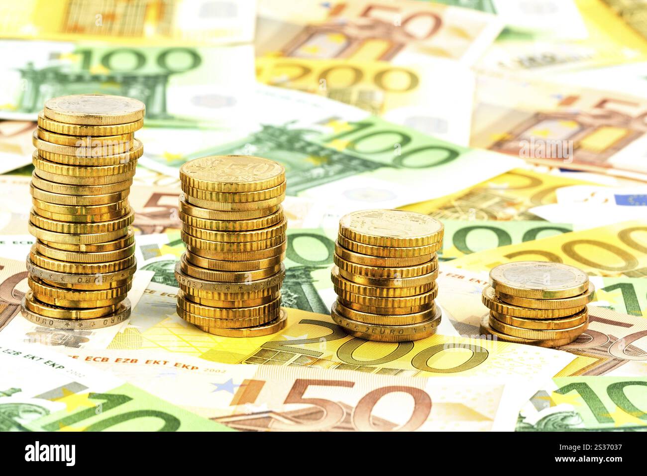 Pila di monete, curva discendente, foto simbolica per il calo dei tassi di interesse e dei costi Foto Stock