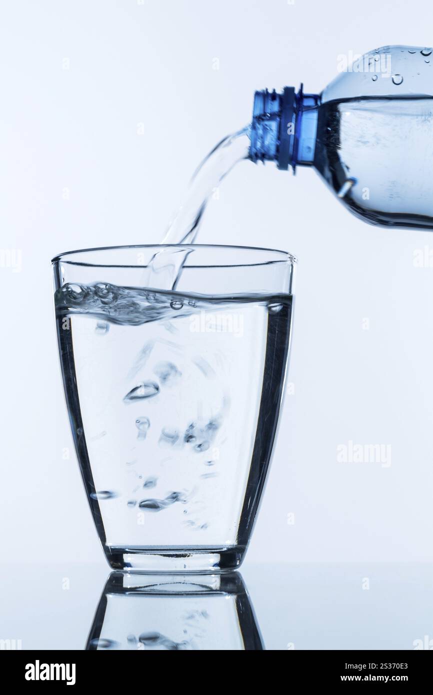L'acqua viene versata da una bottiglia in un bicchiere, foto simbolica per l'acqua potabile, la domanda e il consumo dell'Austria Foto Stock
