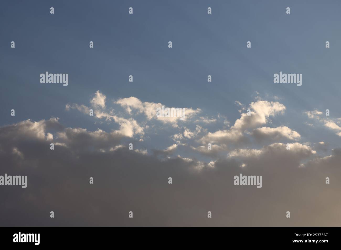 le nuvole più alte di piccole dimensioni emettono un bianco brillante alla luce del sole, al di sopra delle nuvole di tempesta più intense Foto Stock