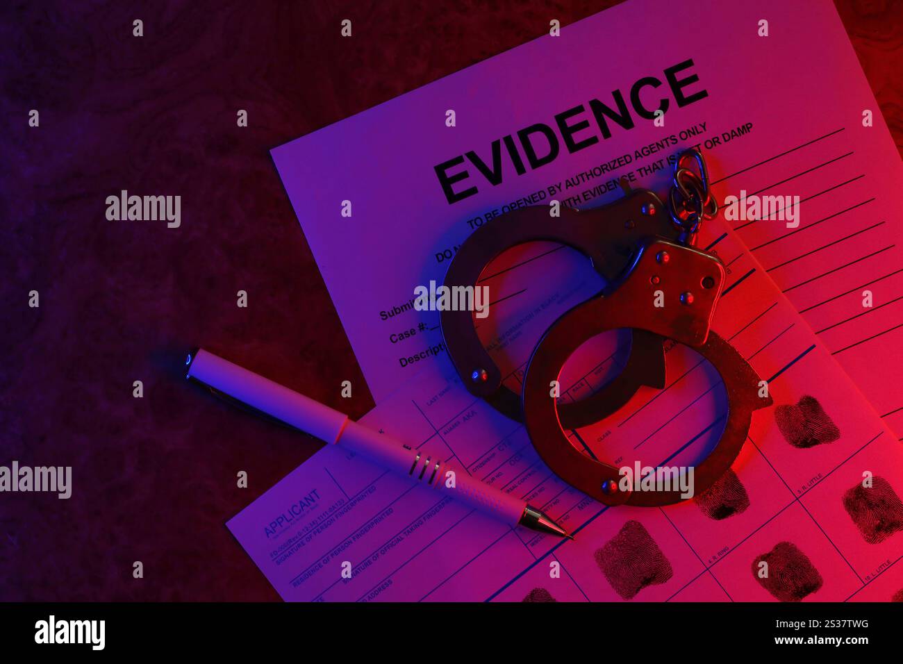 Tessera del richiedente o delle impronte digitali con le manette della polizia sul tavolo in una stanza buia da vicino. Tessera del richiedente o delle impronte digitali con le manette della polizia sul tavolo Foto Stock