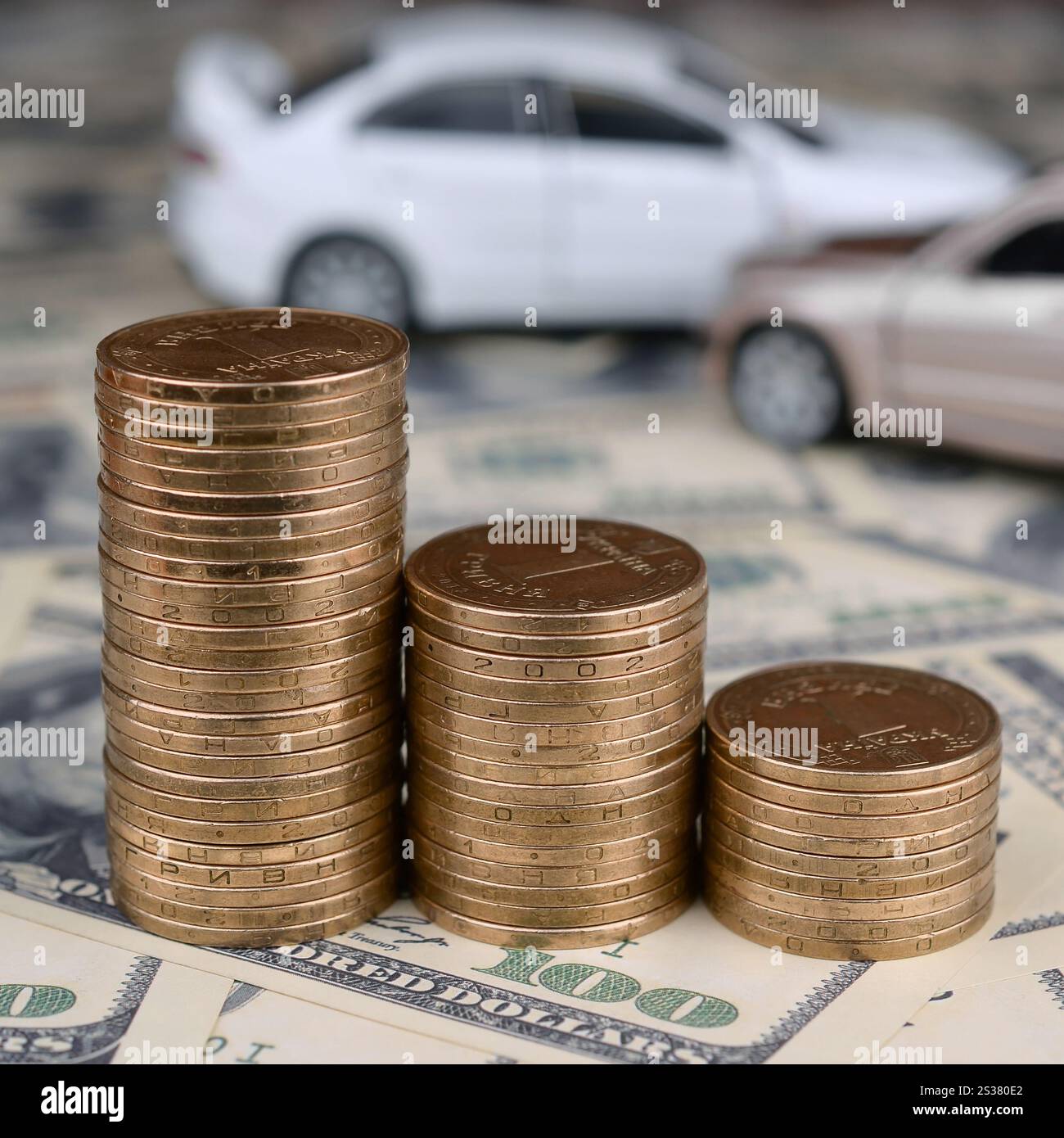 Auto giocattolo in incidente su uno sfondo di banconote da 100 dollari e pile di monete d'oro. Concetto di assicurazione auto. Auto giocattolo in un incidente su un sfondo di 100 Foto Stock