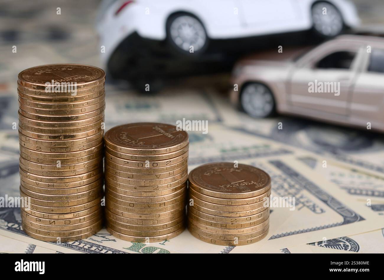 Auto giocattolo in incidente su uno sfondo di banconote da 100 dollari e pile di monete d'oro. Concetto di assicurazione auto. Auto giocattolo in un incidente su un sfondo di 100 Foto Stock