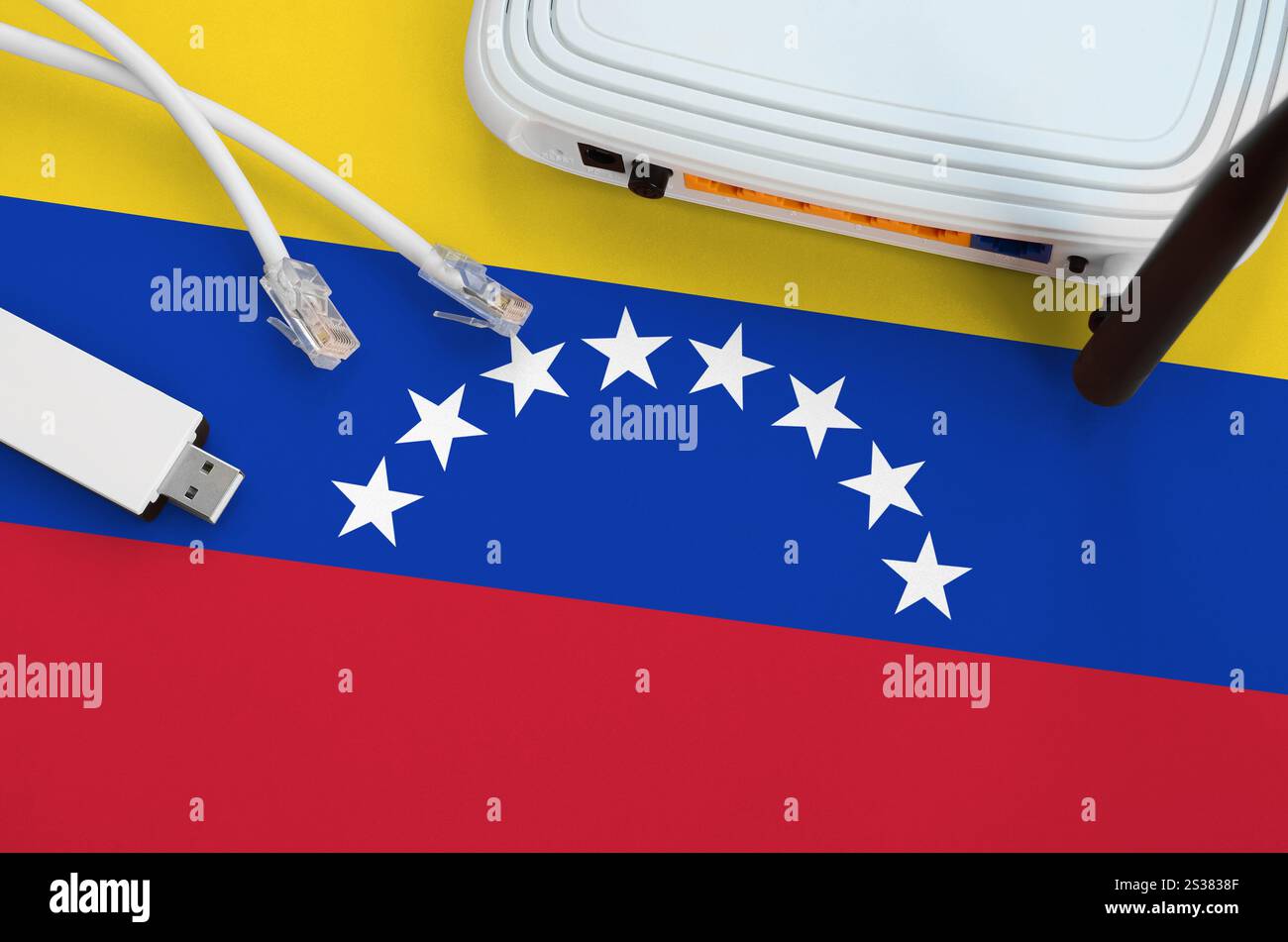Bandiera venezuelana raffigurata sul tavolo con cavo Internet rj45, adattatore wireless usb wi-fi e router. Concetto di connessione a Internet. Bandiera del Venezuela Foto Stock