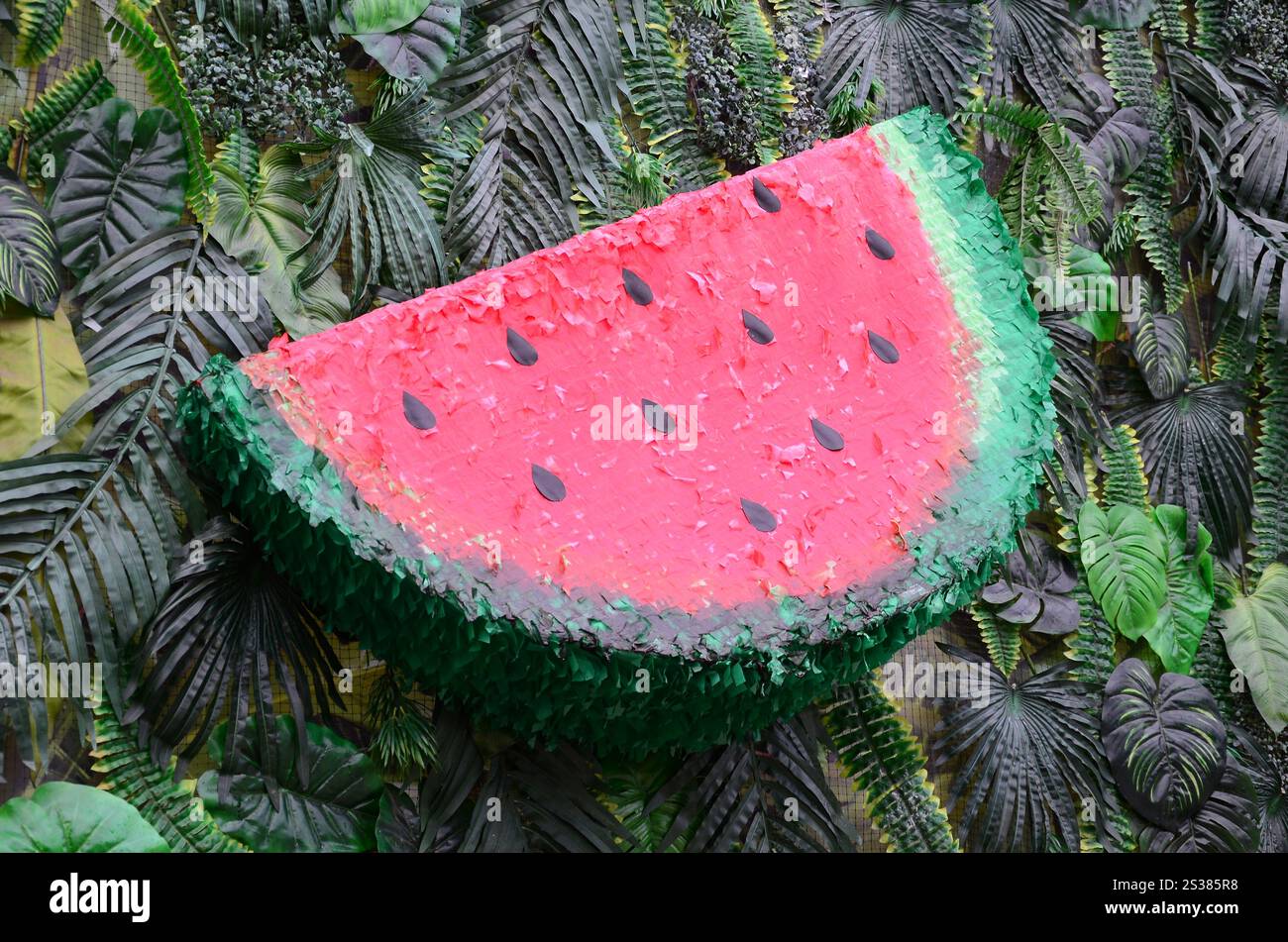 Motivo tropicale con foglie di giungla e fondo floreale di frutta anguria. Fetta di anguria di plastica con foglia di palma. Motivo tropicale con giungla Foto Stock