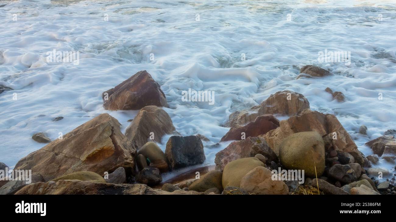 Onde durante una tempesta che si schianta sulle rocce della costa Foto Stock