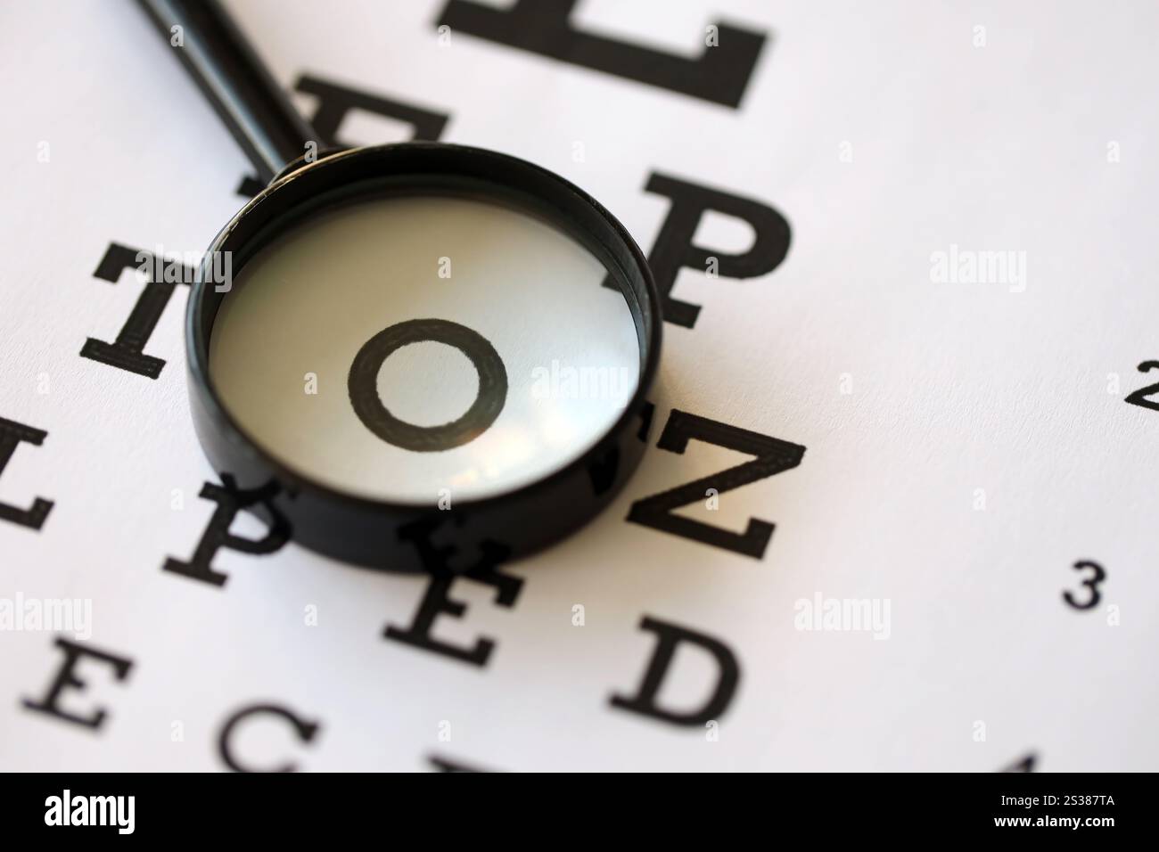 La lente di ingrandimento mette a fuoco chiaramente le lettere del grafico oculare e si trova su carta per test oculari da vicino. La lente di ingrandimento mette a fuoco le lettere del grafico oculare in modo chiaro e. Foto Stock