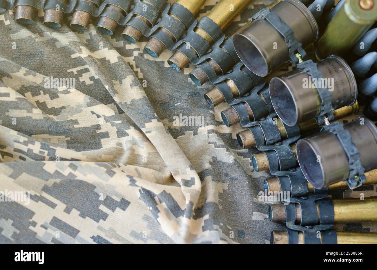 Il tessuto dell'esercito ucraino e i proiettili a cintura della mitragliatrice si trovano su un mimetismo militare pixeled ucraino da vicino. Tessuto dell'esercito ucraino e cintura di mitragliatrice Foto Stock
