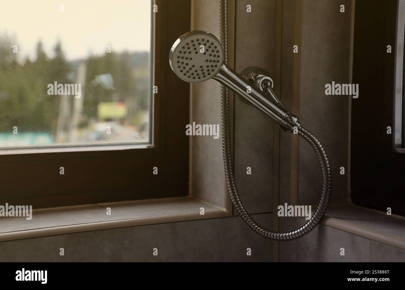 Doccia argentata nel moderno bagno dell'hotel con luce naturale dalla finestra. Doccia argentata nel moderno bagno dell'hotel con luce naturale Foto Stock