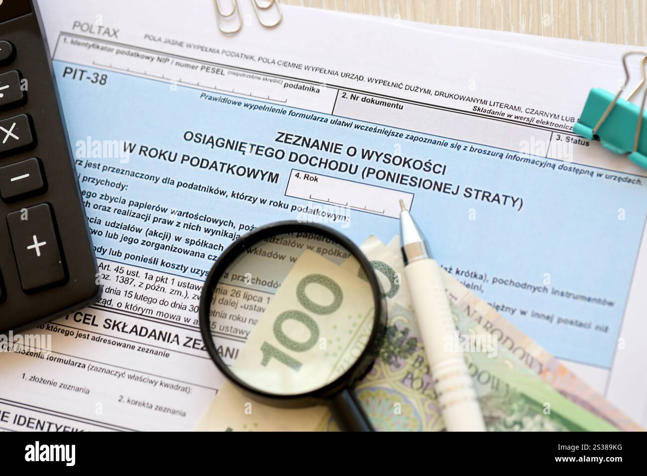 Dichiarazione dell'importo del reddito da lavoro o delle perdite subite, moduli fiscali PIT-38 sul contabile con pennarelli e banconote in denaro zloty polacco primo piano. Foto Stock
