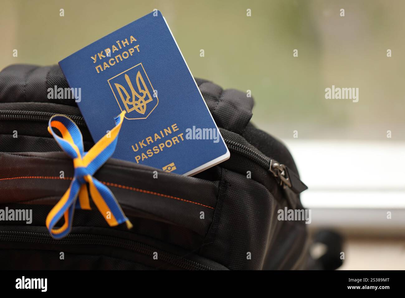 Passaporto biometrico ucraino su zaino turistico nero con nastro ucraino da vicino. Passaporto biometrico ucraino su zaino turistico nero Foto Stock