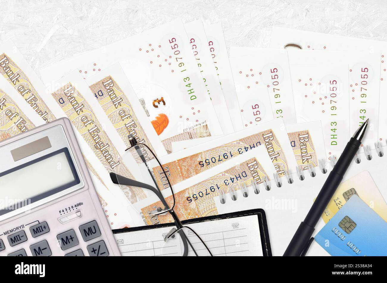 Banconote da 10 sterline inglesi e calcolatrice con occhiali e penna. Concetto di stagione del pagamento delle imposte o soluzioni di investimento. Pianificazione finanziaria o contabile Foto Stock