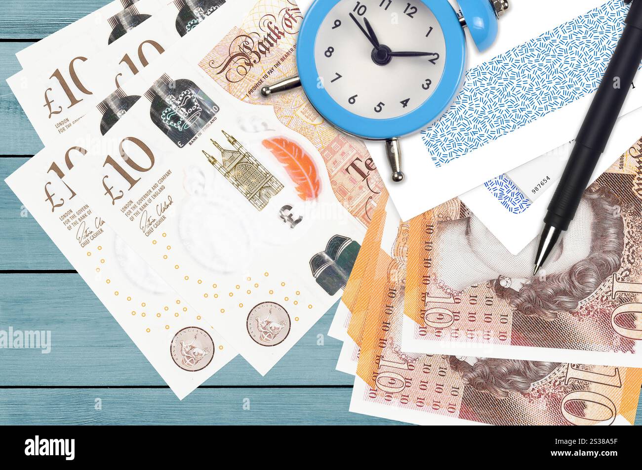 Bollette da 10 sterline britanniche e sveglia con penna e buste. Concetto di stagione fiscale, termine di pagamento per credito o prestito. Operazioni finanziarie utilizzando Foto Stock