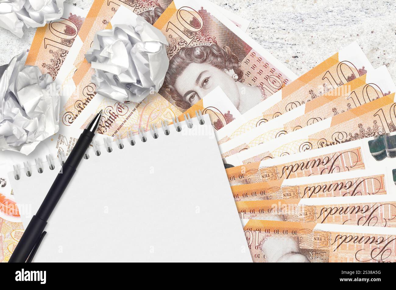 Banconote da 10 sterline britanniche e palle di carta increspata con blocco note. Idee cattive o meno di concetto di ispirazione. Alla ricerca di idee per l'investimento. 10 Foto Stock