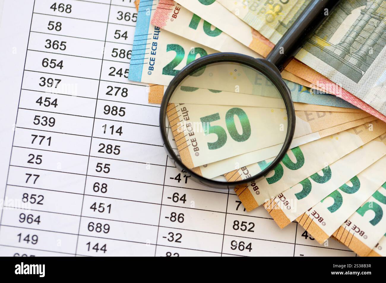 Concetto di business e risparmio con molte banconote in euro e lente d'ingrandimento in primo piano. Concetto di business e risparmio con molte bollette in euro e. Foto Stock