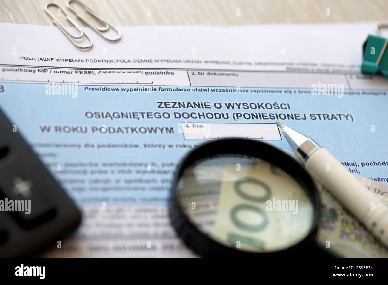 Dichiarazione dell'importo del reddito da lavoro o delle perdite subite, moduli fiscali PIT-38 sul contabile con pennarelli e banconote in denaro zloty polacco primo piano. Foto Stock