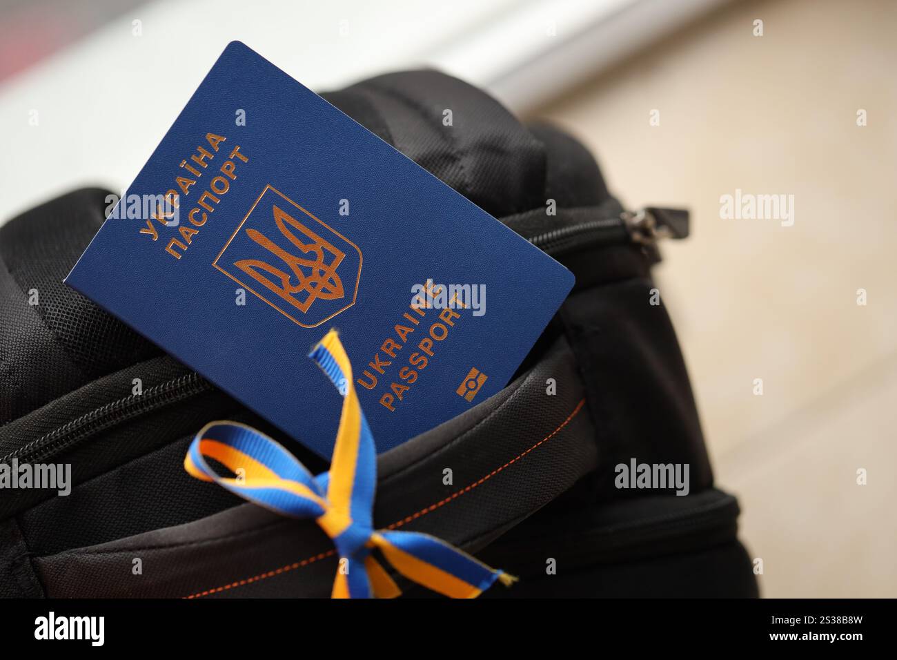 Passaporto biometrico ucraino su zaino turistico nero con nastro ucraino da vicino. Passaporto biometrico ucraino su zaino turistico nero Foto Stock