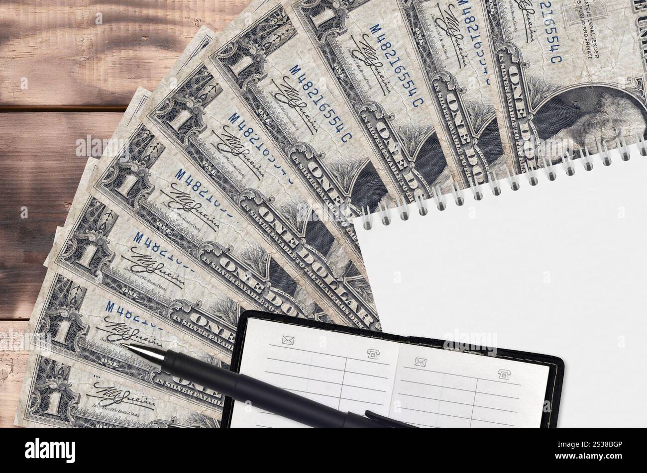 1 dollaro USA di banconote, ventola e blocco note con rubrica e penna nera. Concetto di pianificazione finanziaria e strategia aziendale. Contabilità e investimenti. 1 Foto Stock