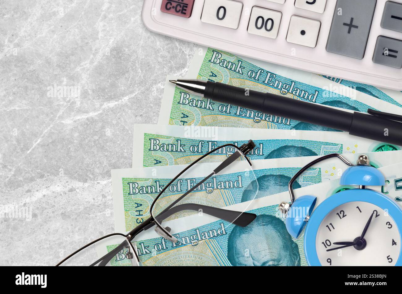 Banconote da 5 sterline inglesi e calcolatrice con occhiali e penna. Concetto di stagione del prestito aziendale o del pagamento delle imposte. Pianificazione finanziaria e tempo per pagare le tasse. 5 Foto Stock
