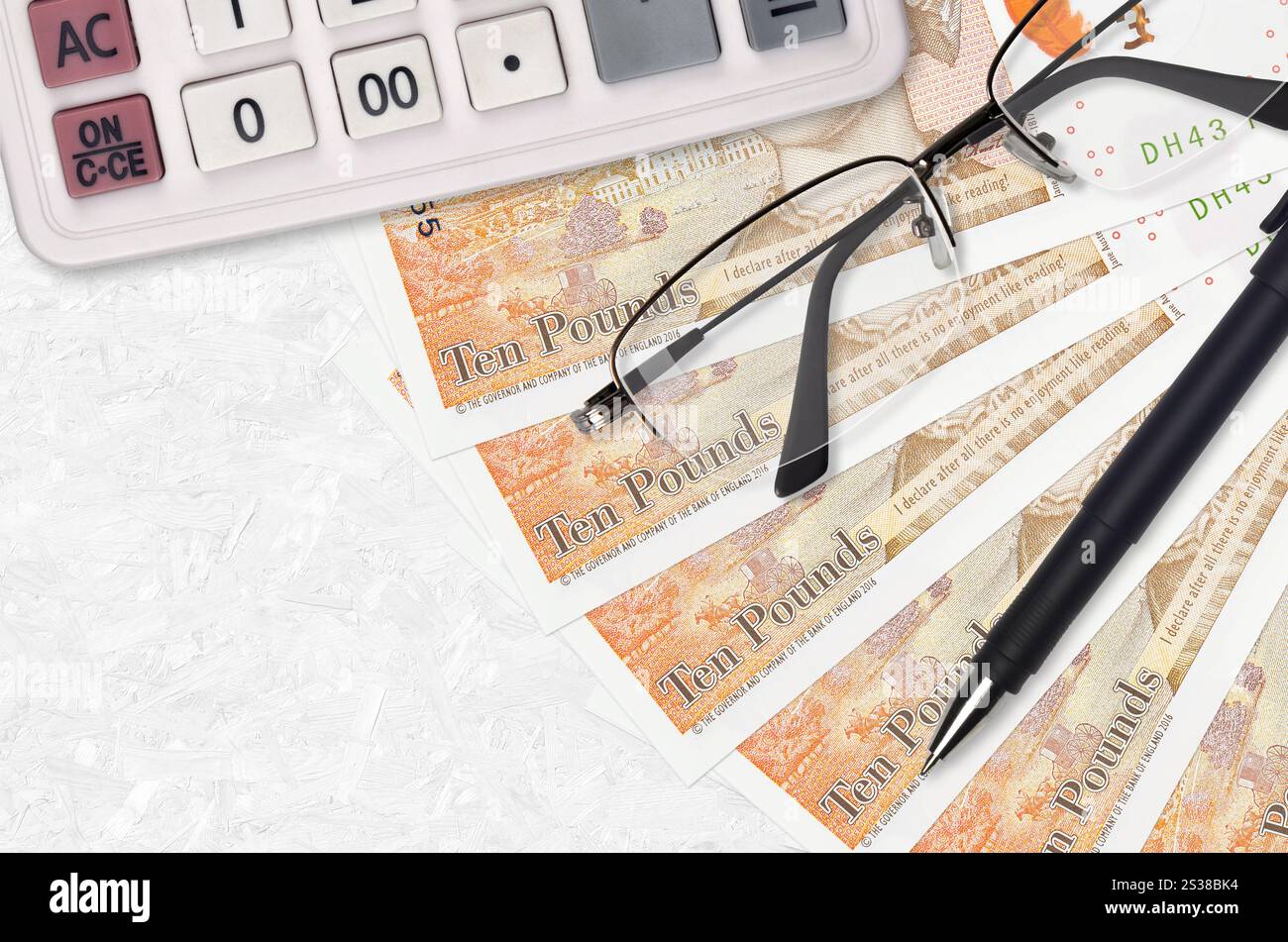 10 sterline inglesi ventilatore e calcolatrice con occhiali e penna. Concetto di stagione del prestito aziendale o del pagamento delle imposte. Pianificazione finanziaria. 10 sterline britanniche Foto Stock