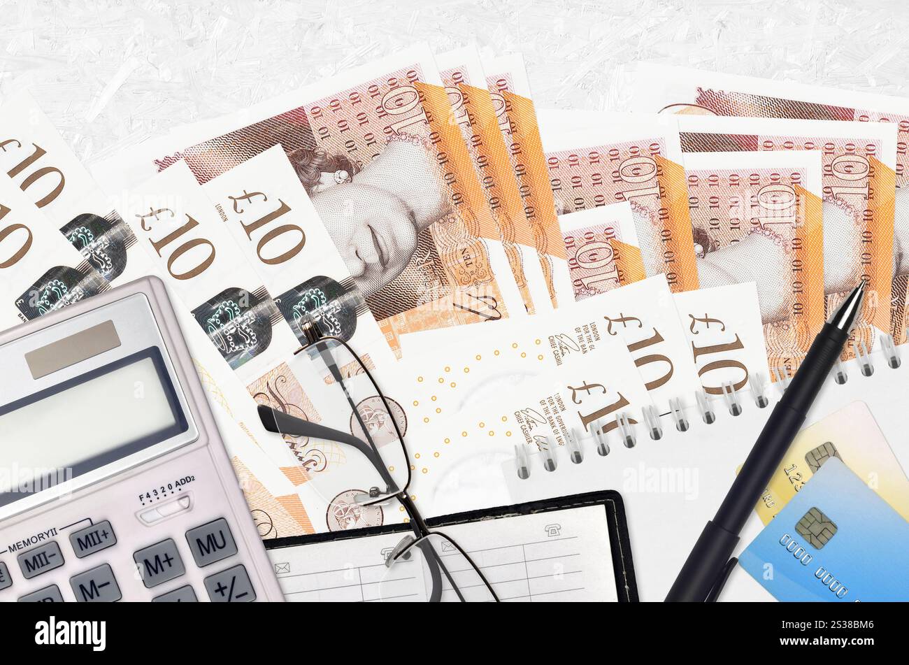Banconote da 10 sterline inglesi e calcolatrice con occhiali e penna. Concetto di stagione del pagamento delle imposte o soluzioni di investimento. Pianificazione finanziaria o contabile Foto Stock