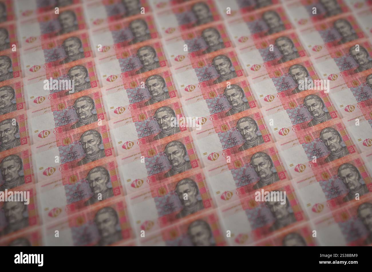 10 banconote ucraine di hryvnias stampate in un trasportatore di produzione di denaro illegale. Collage di molte banconote false. Concetto di lavoro di massa dei contraffattori. 10 Foto Stock