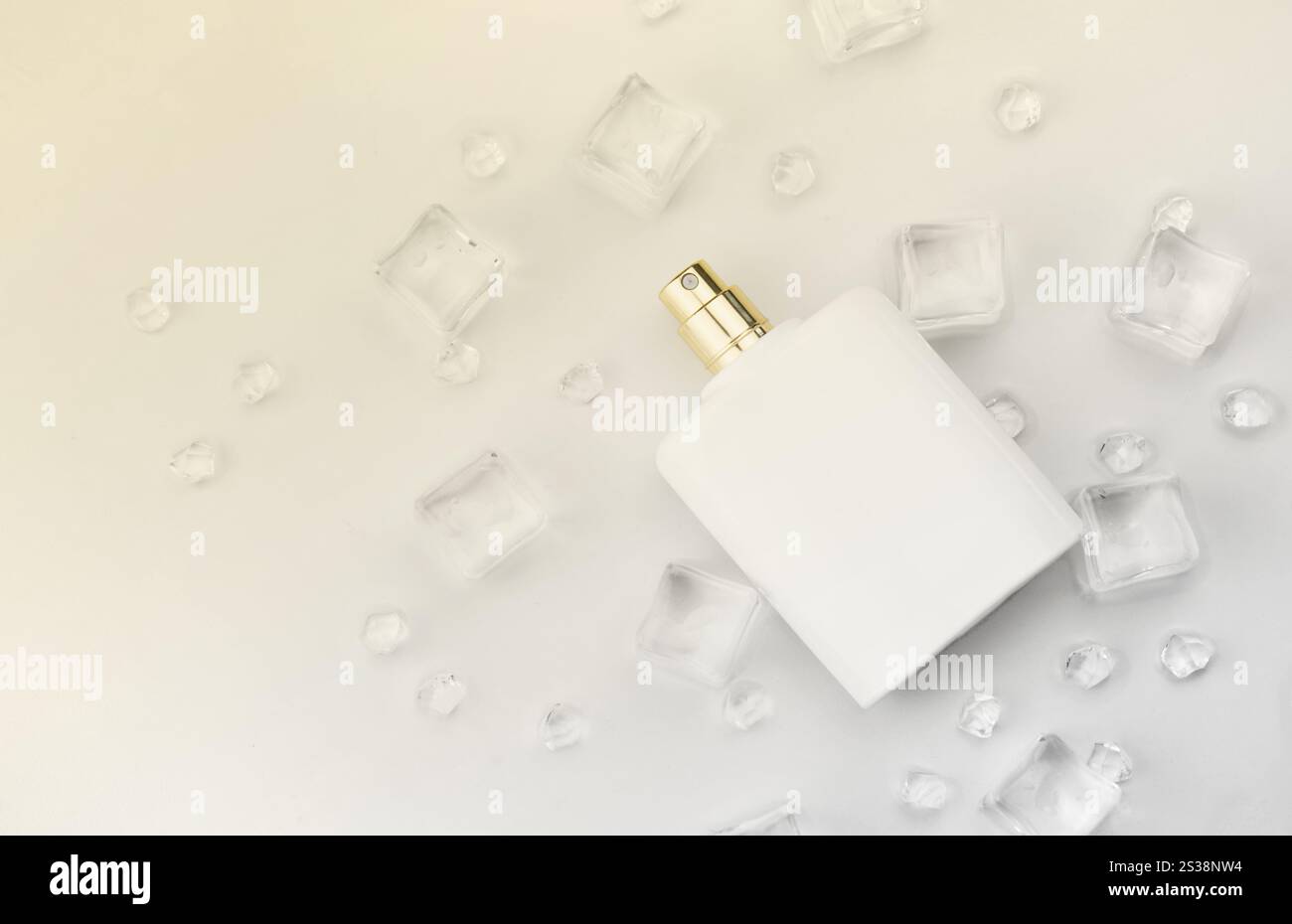 Bottiglia bianca di profumo femminile, fotografia obiettiva di bottiglia di profumo in cubetti di ghiaccio e acqua su tavola bianca. Vista dall'alto. Foto prodotto mockup, Foto Stock