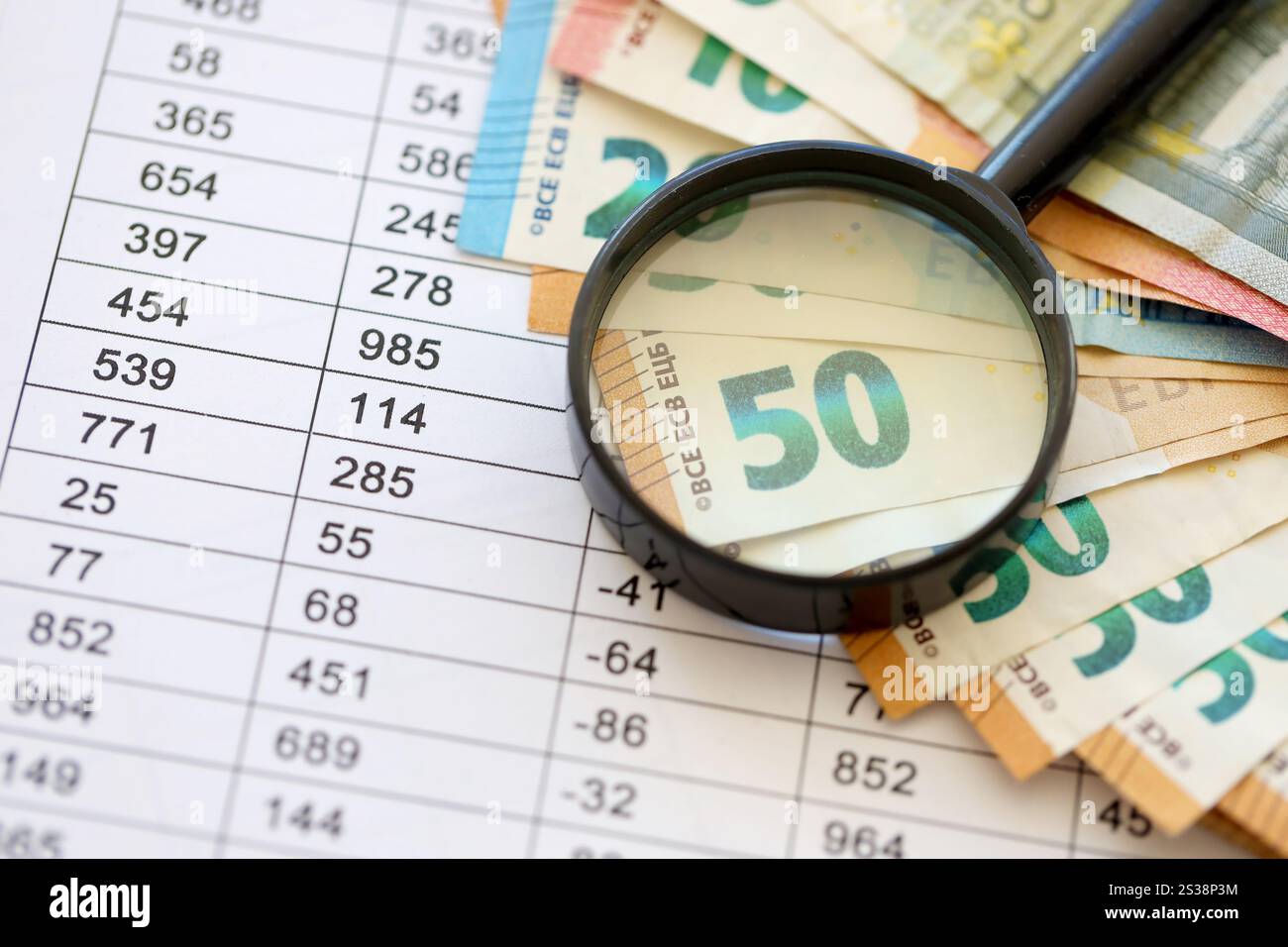 Concetto di business e risparmio con molte banconote in euro e lente d'ingrandimento in primo piano. Concetto di business e risparmio con molte bollette in euro e. Foto Stock