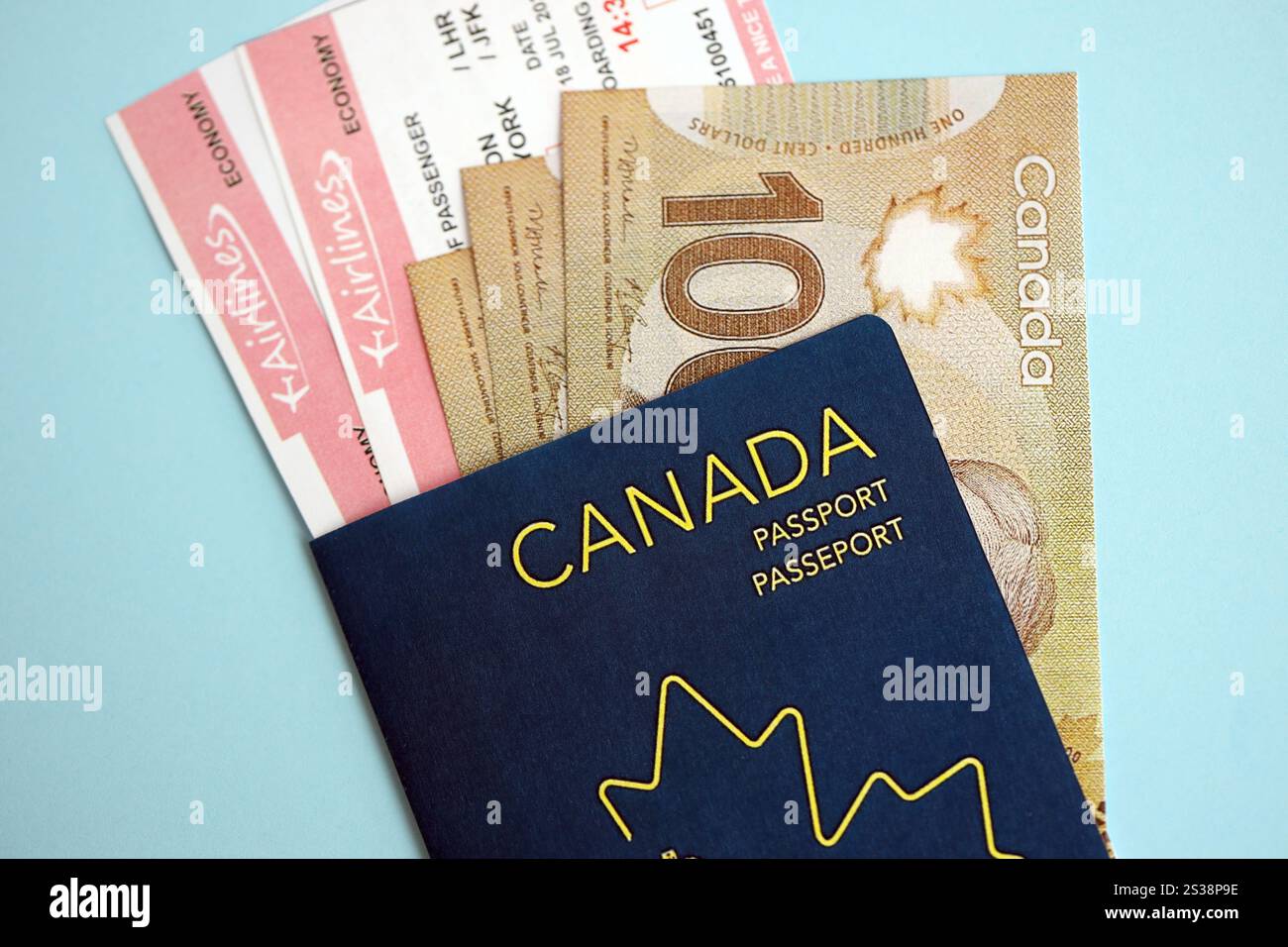 Passaporto canadese con soldi e biglietti aerei su sfondo blu da vicino. Concetto di turismo e viaggio. Passaporto canadese con soldi e compagnia aerea Foto Stock