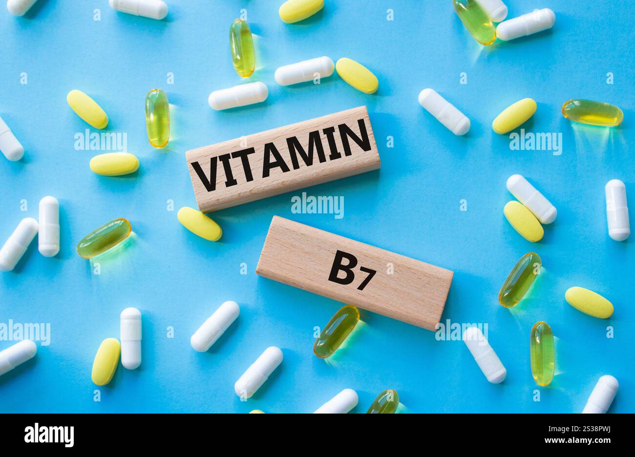 Simbolo della vitamina B7. Parola concettuale vitamina B7 su blocchi di legno. Bellissimo sfondo blu con pillole. Medicina e vitamina B7. Copia spazio Foto Stock