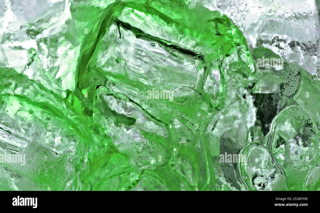 Shot macro di una bevanda ghiacciata con cubetti di ghiaccio verde e bollicine. Rinfrescante bevanda ghiacciata verde da vicino Foto Stock
