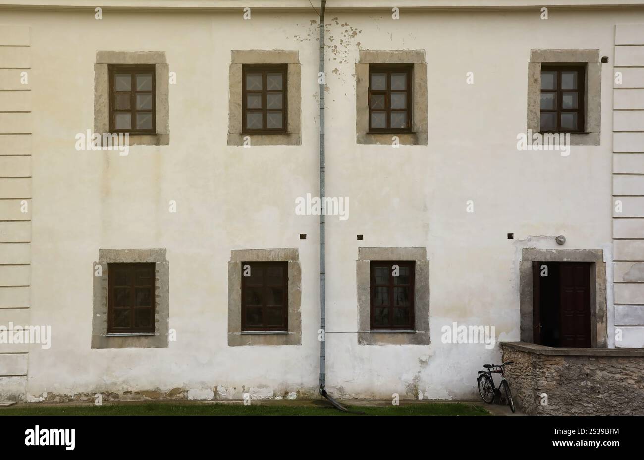 Finestre in vetro su antiche mura bianche del vecchio castello medievale nel sobborgo europeo da vicino. Finestre in vetro su bianco antico muro di vecchio castello medievale Foto Stock