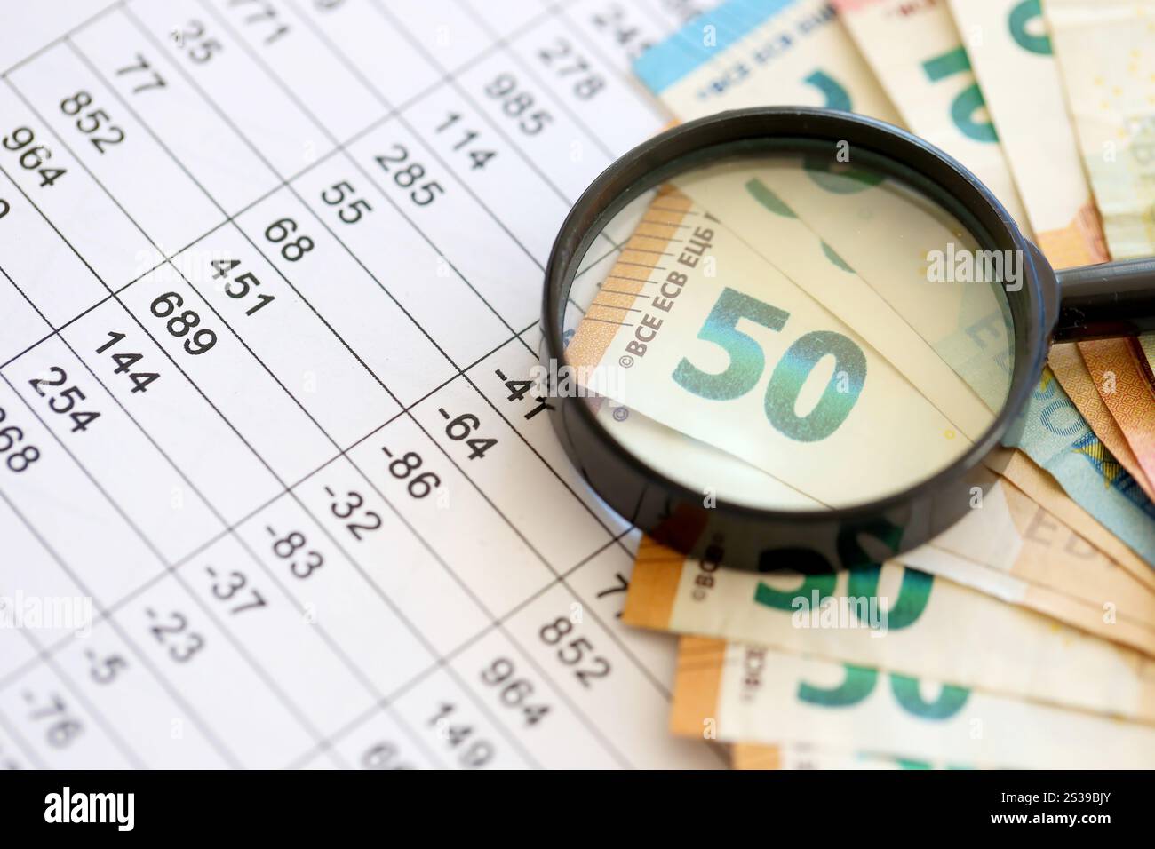 Concetto di business e risparmio con molte banconote in euro e lente d'ingrandimento in primo piano. Concetto di business e risparmio con molte bollette in euro e. Foto Stock