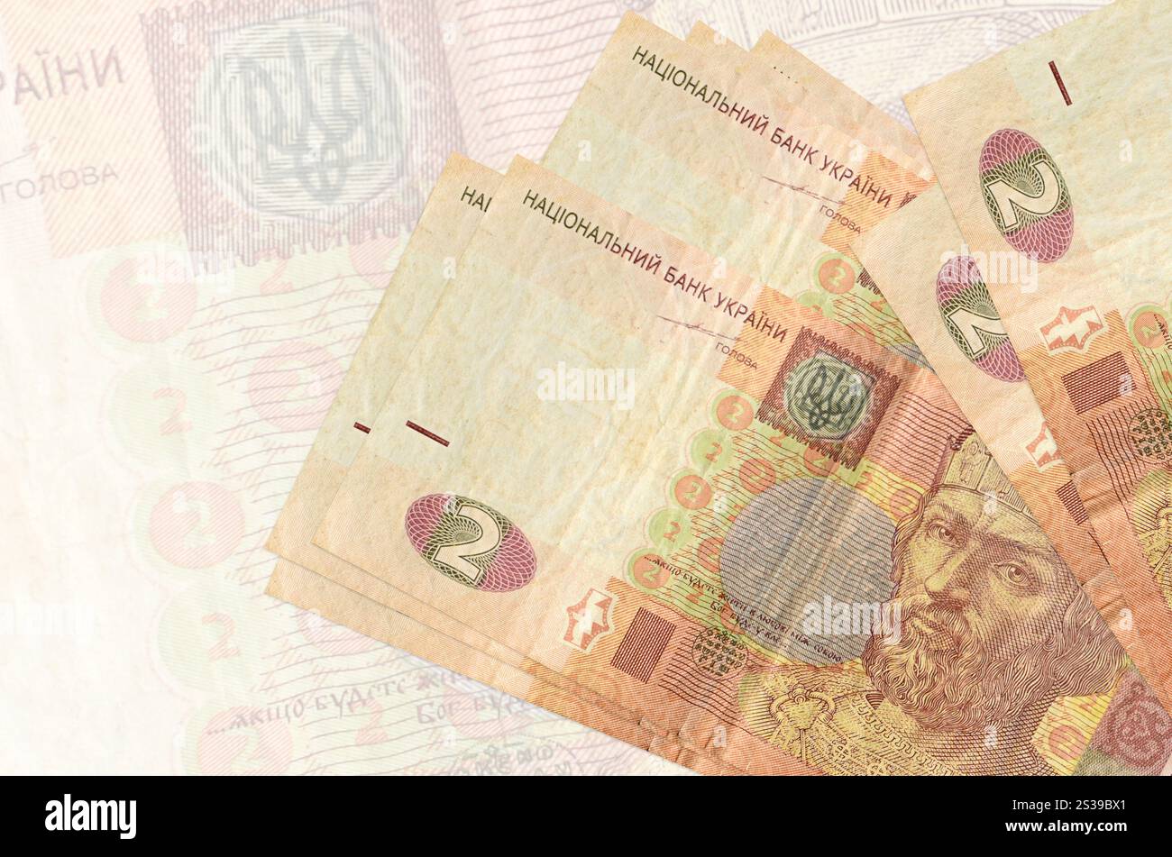 2 le banconote ucraine in hryvnias si trovano in una pila sullo sfondo di una grande banconota semi-trasparente. Presentazione astratta della moneta nazionale. Affari Foto Stock