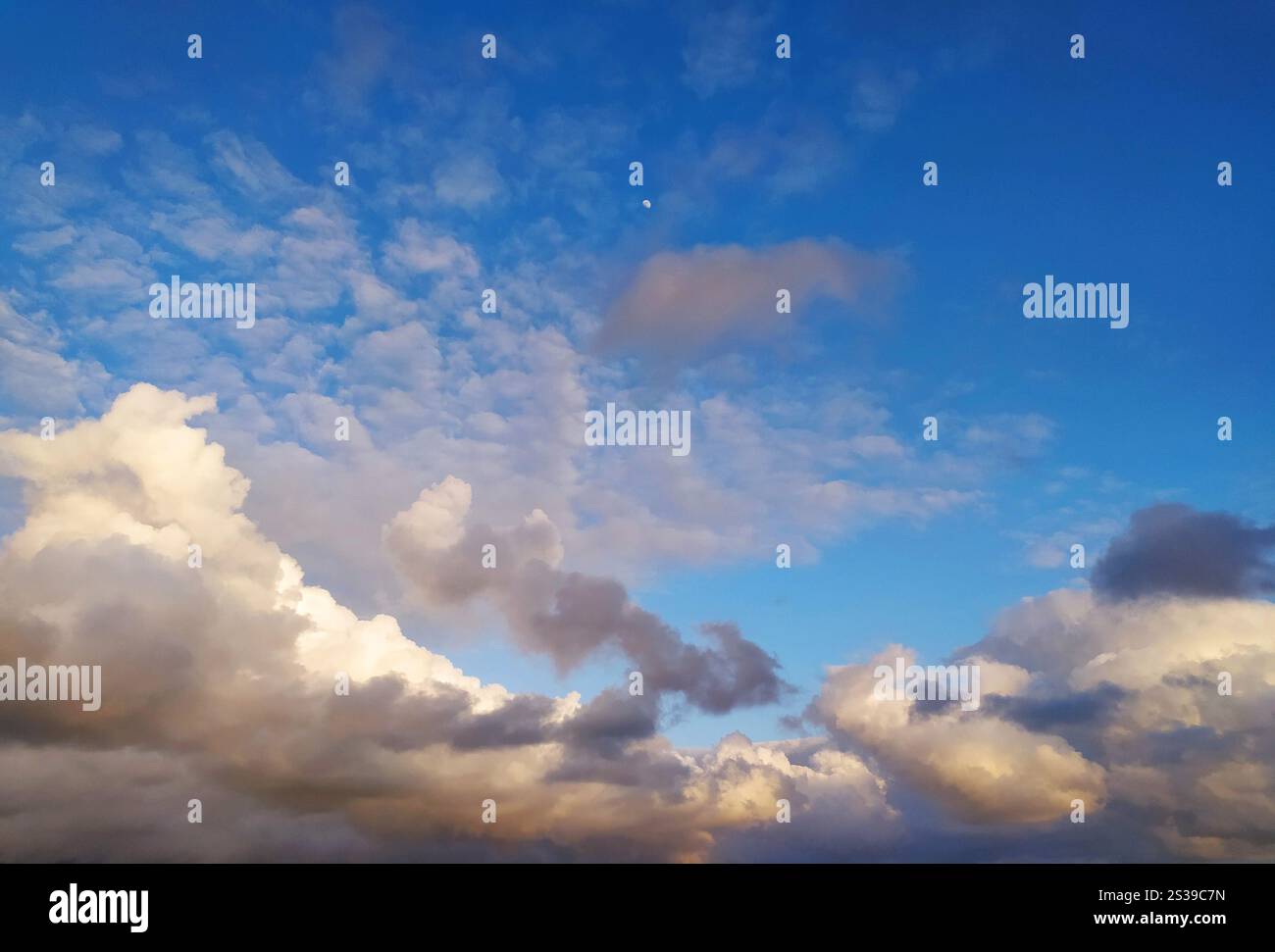 Il sole sta tramontando, proiettando un caldo bagliore sulle nuvole del cielo. I colori vibranti del tramonto si riflettono nelle nuvole, creando un'atmosfera drammatica Foto Stock