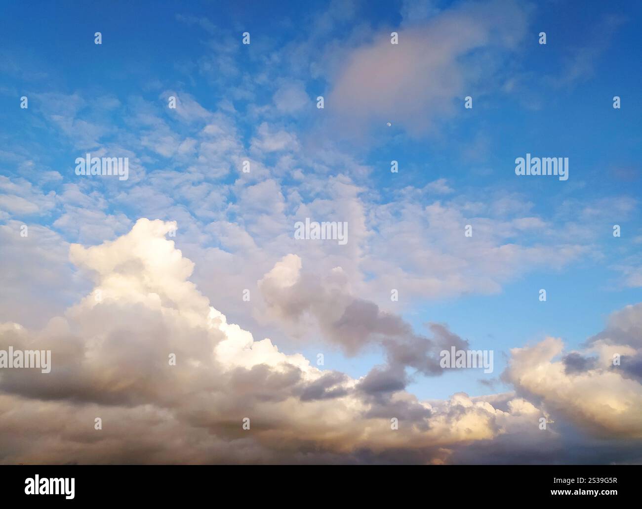 Il sole sta tramontando, proiettando un caldo bagliore sulle nuvole del cielo. I colori vibranti del tramonto si riflettono nelle nuvole, creando un'atmosfera drammatica Foto Stock