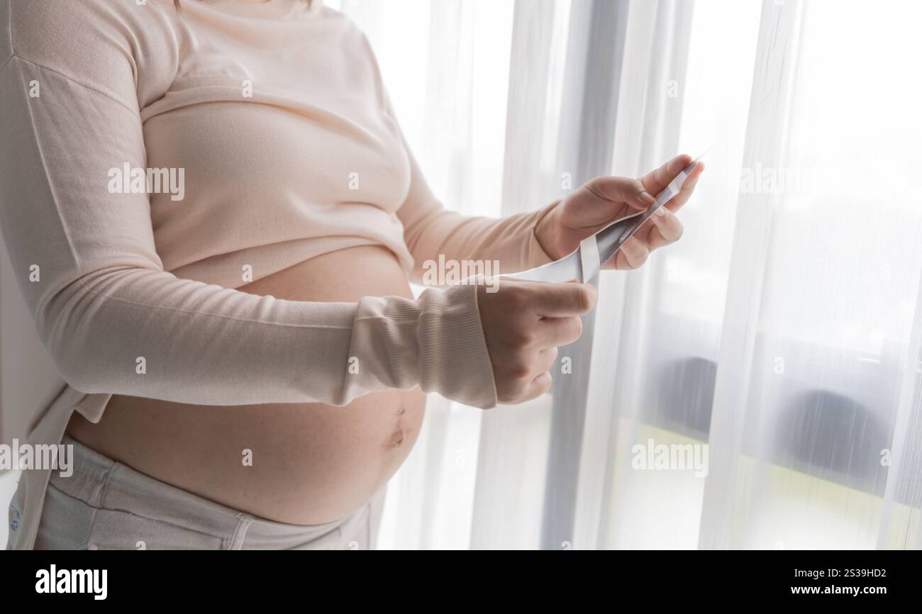 Donna asiatica incinta che tiene il bambino a ultrasuoni risultato dell'immagine dal medico. Felice idea di assistenza sanitaria mamma. Foto Stock