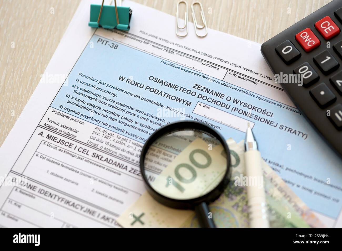 Dichiarazione dell'importo del reddito da lavoro o delle perdite subite, moduli fiscali PIT-38 sul contabile con pennarelli e banconote in denaro zloty polacco primo piano. Foto Stock