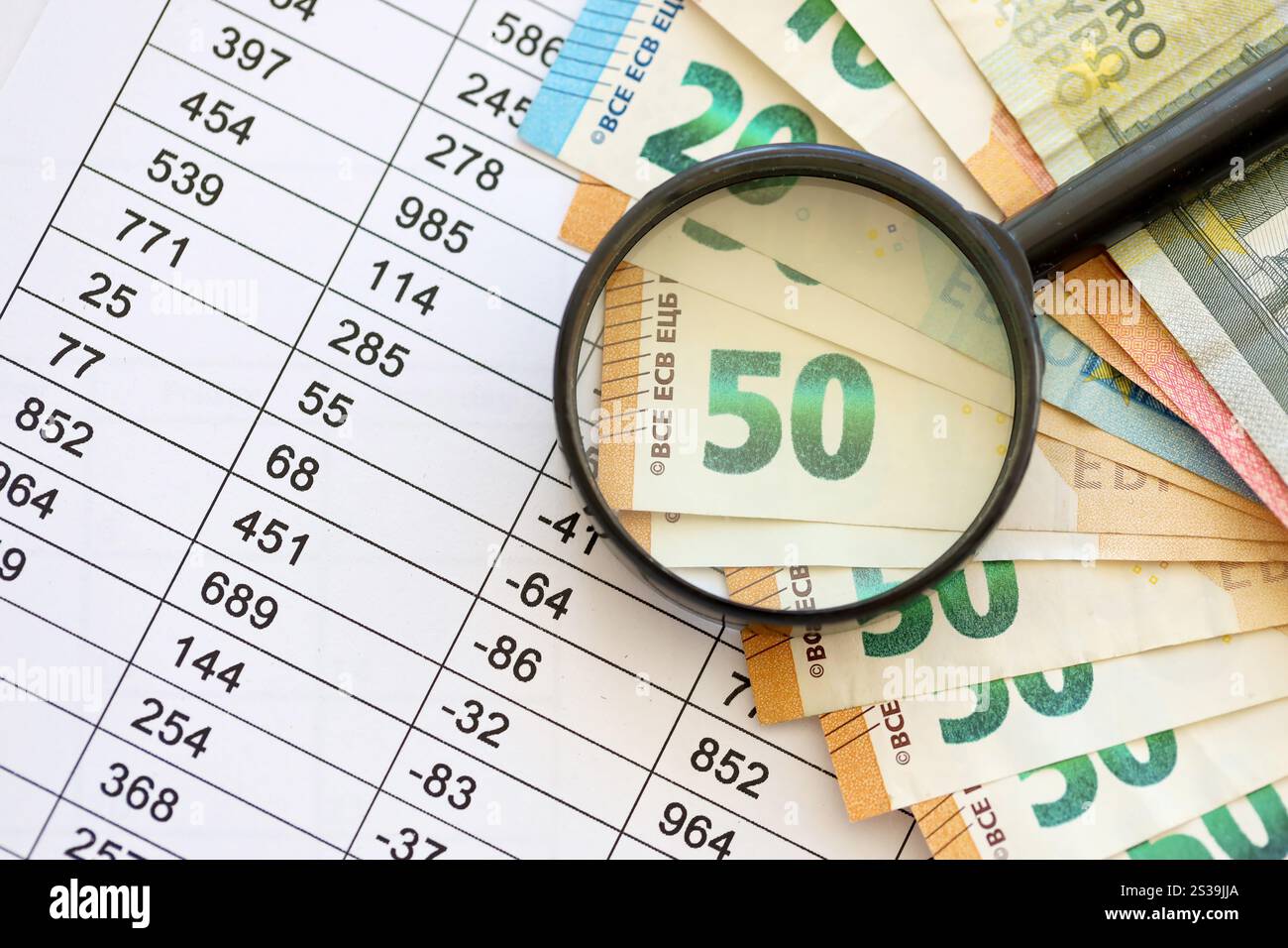 Concetto di business e risparmio con molte banconote in euro e lente d'ingrandimento in primo piano. Concetto di business e risparmio con molte bollette in euro e. Foto Stock