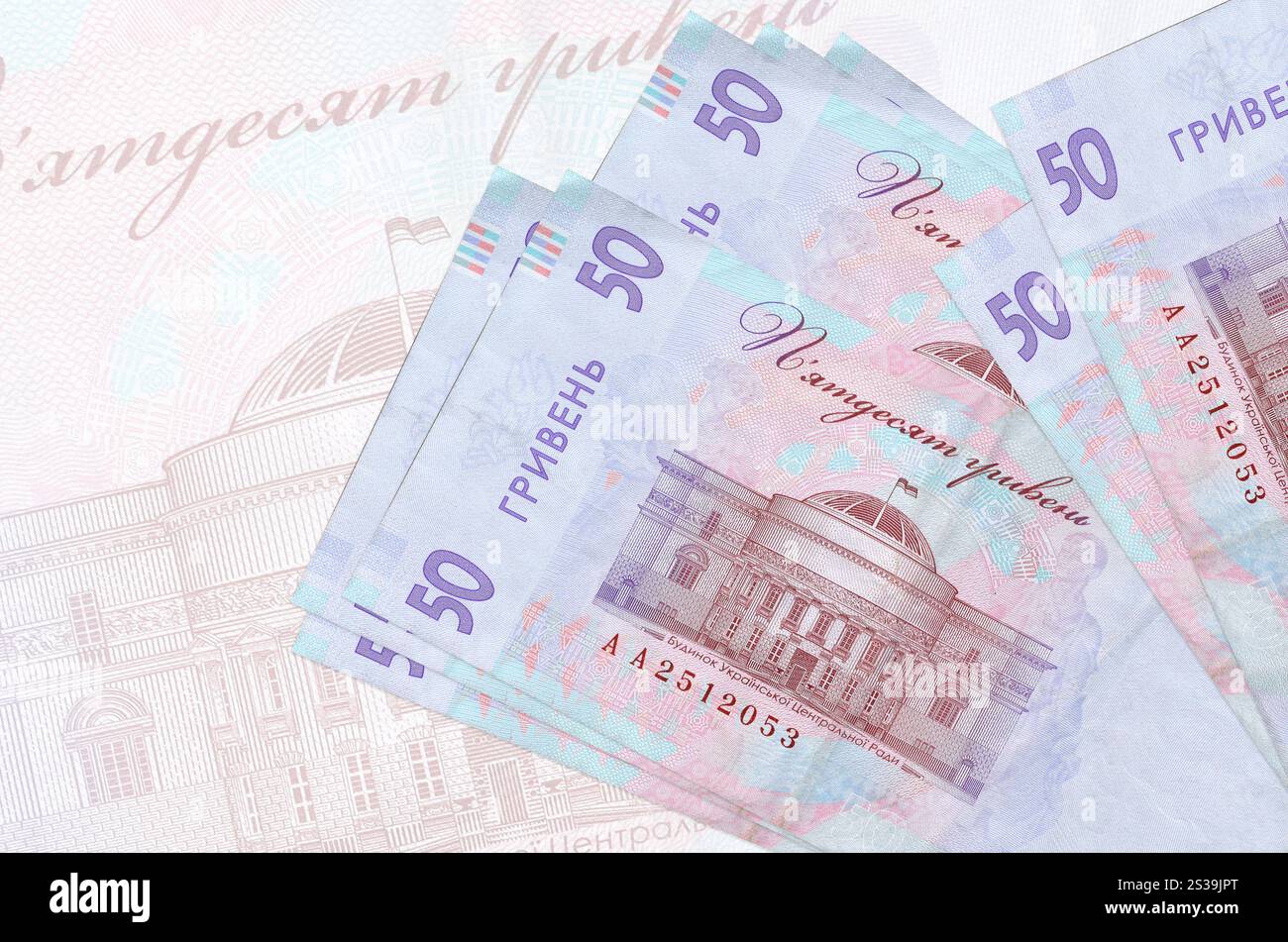 50 banconote ucraine in hryvnias si trovano in una pila sullo sfondo di una grande banconota semi-trasparente. Presentazione astratta della moneta nazionale. Affari Foto Stock