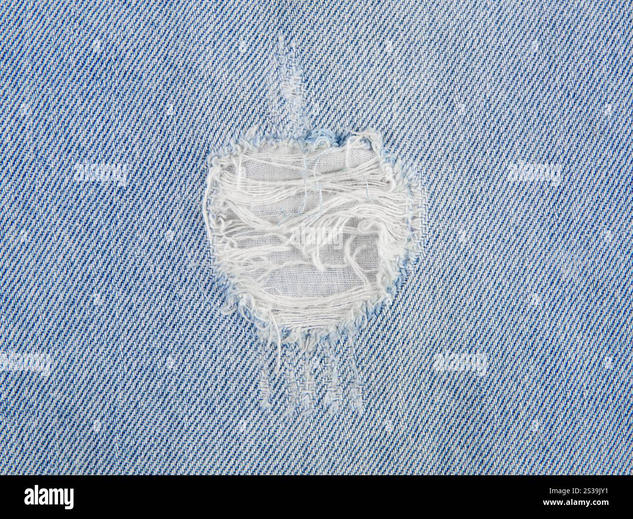 Vista ravvicinata dei jeans in denim azzurro con buco strappato. Vista orizzontale, ripresa in studio, ampio spazio di copia. Foto Stock