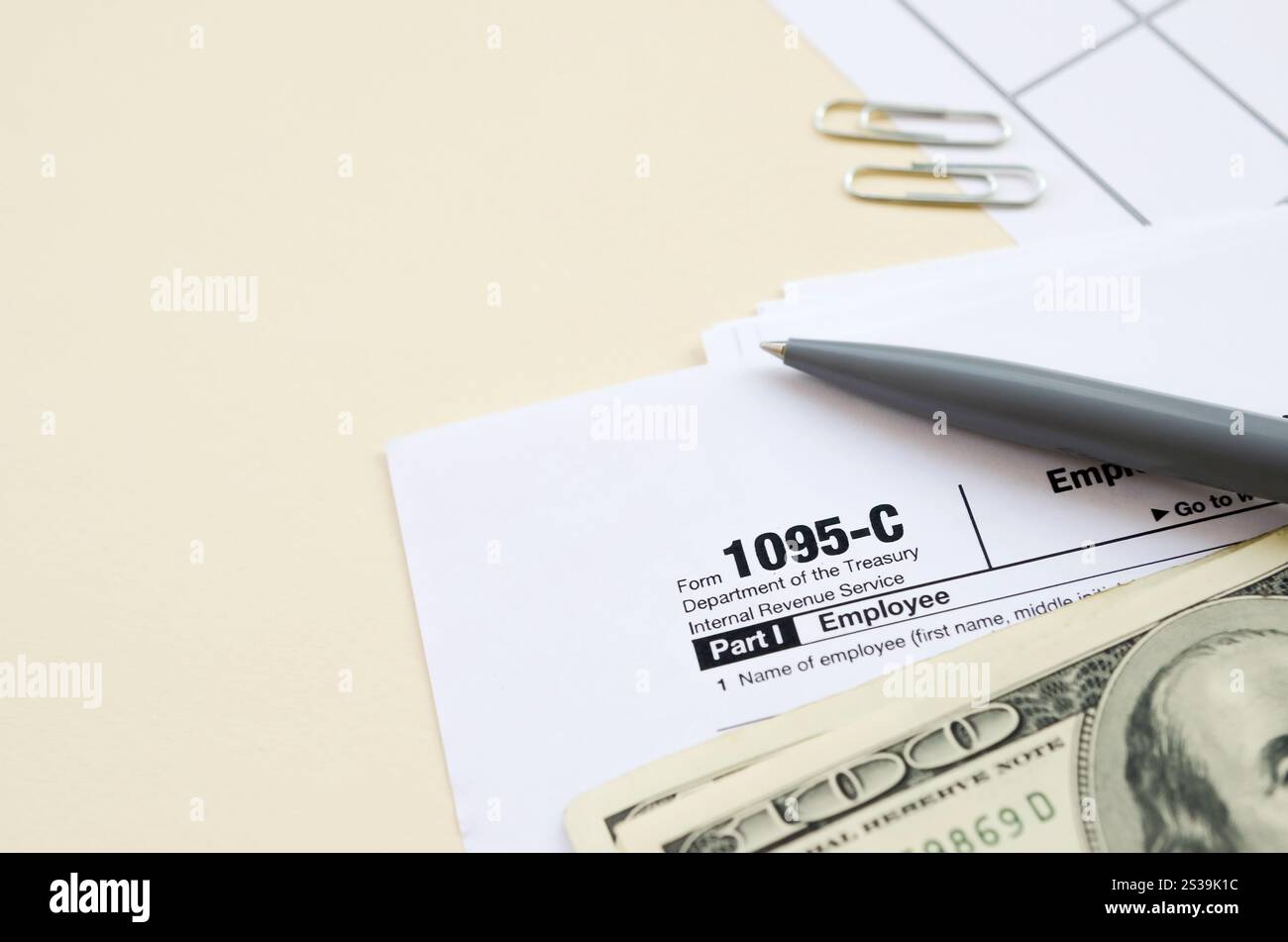 Modulo IRS 1095-C datore di lavoro-fornito offerta di assicurazione sanitaria e copertura tassa in bianco giace con penna e molte centinaia di banconote di dollari sulla pagina del calendario. Tassa Foto Stock