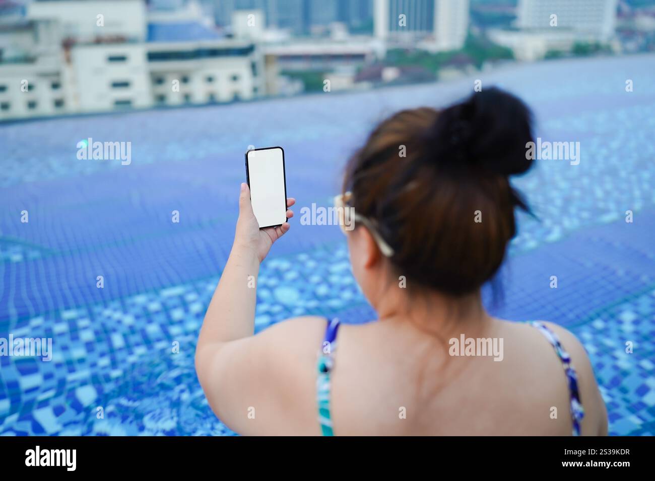 Donna obesa vacanza che viaggia a mano utilizzando il telefono telefono lo spazio vuoto lo schermo lo smartphone che si rilassa in piscina. Foto Stock