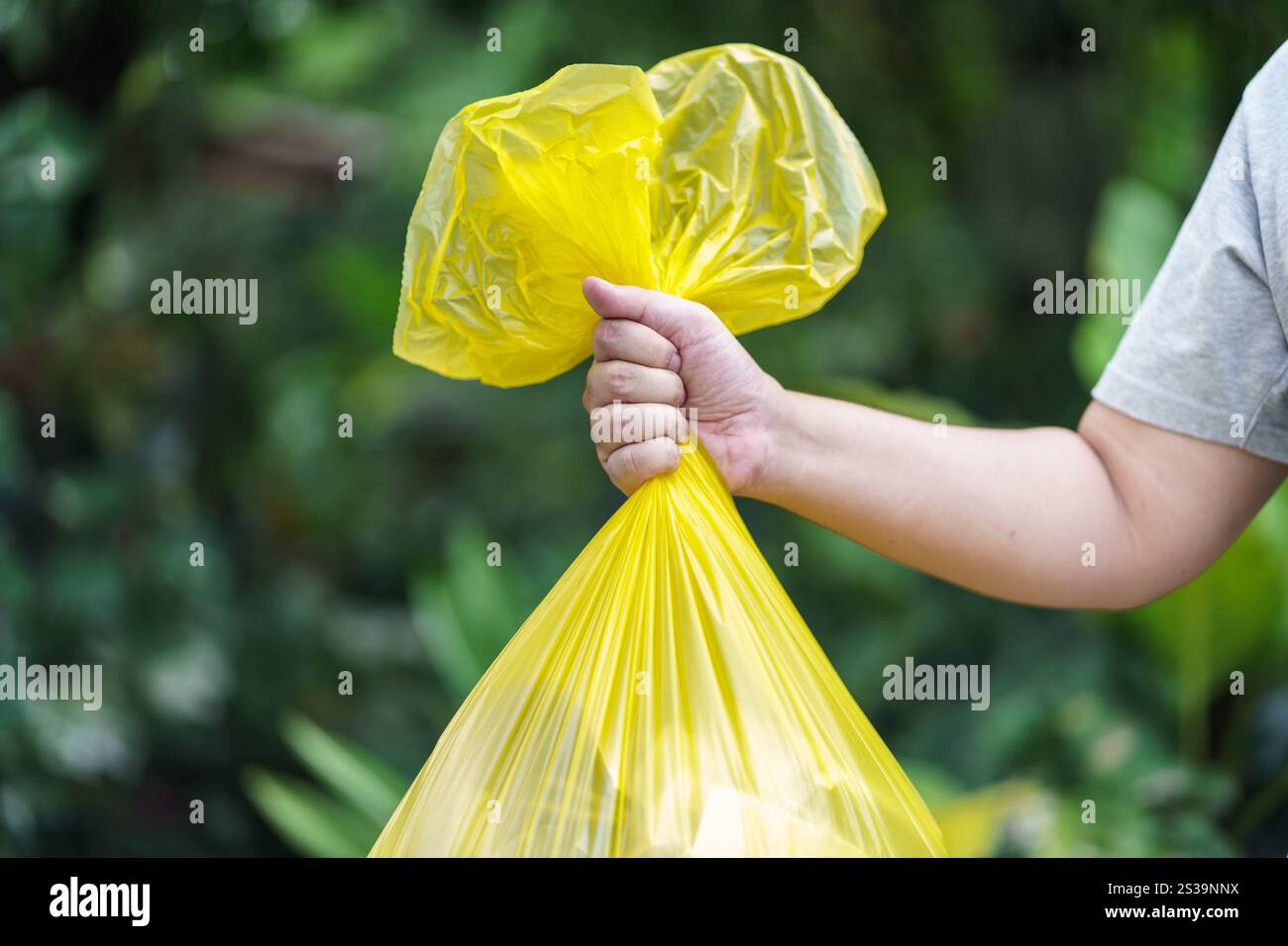 Man Volunteer Charity che tiene immondizia sacca gialla e bottiglia di plastica spazzatura per riciclare e pulire. Foto Stock