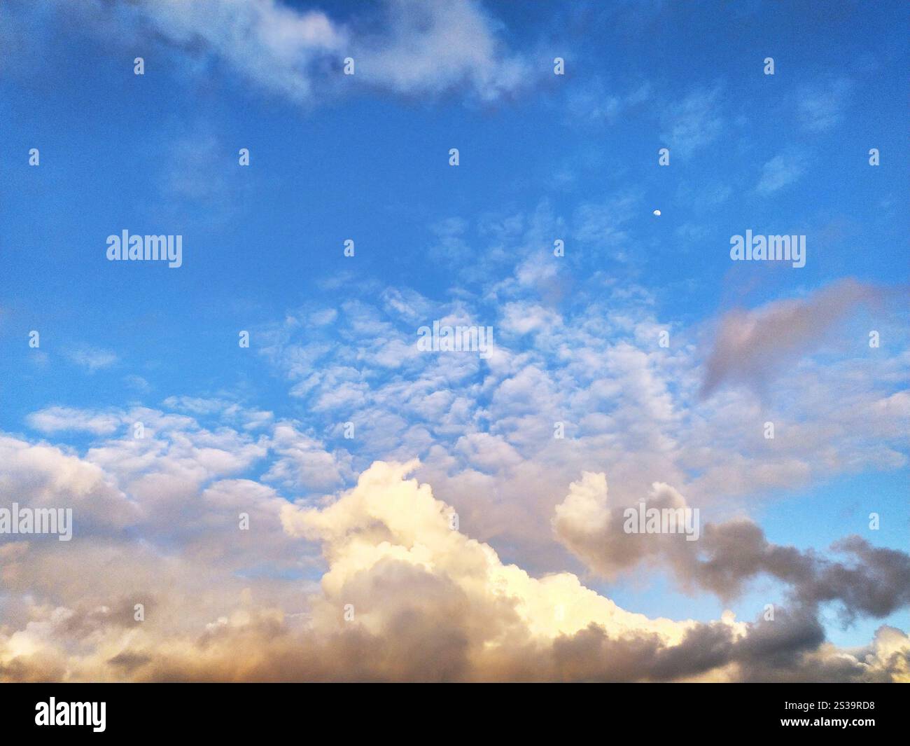 Il sole sta tramontando, proiettando un caldo bagliore sulle nuvole del cielo. I colori vibranti del tramonto si riflettono nelle nuvole, creando un'atmosfera drammatica Foto Stock