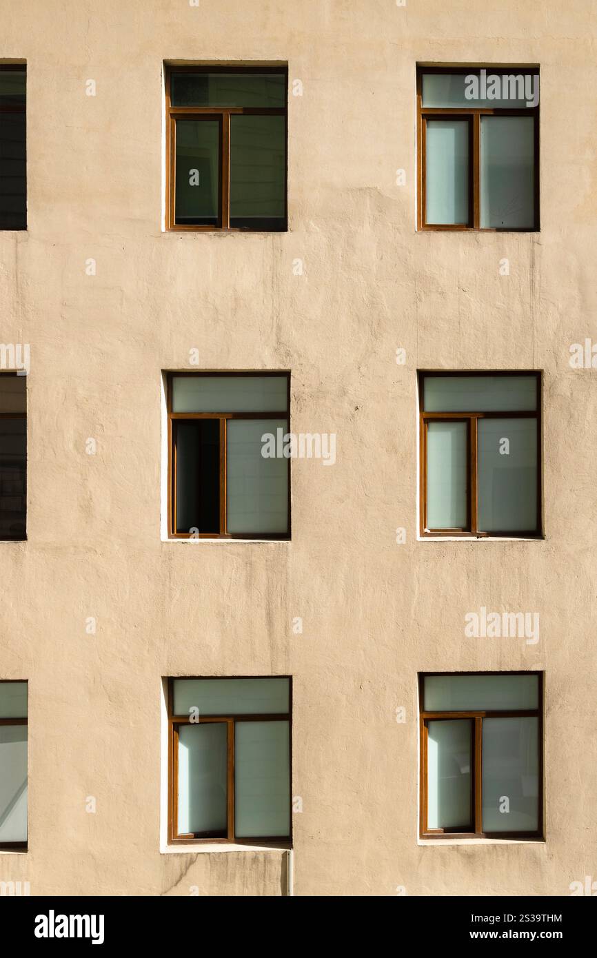 sfondo urbano verticale - parete intonacata gialla dell'appartamento con finestre Foto Stock